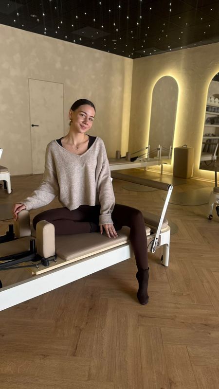 Lektorka sedí na reformeri v sále so svietiacimi oblúkmi